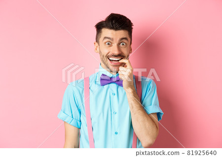 Excited and tempted young guy wants something, biting fingernail with temptation looking at camera, choosing product, standing over pink background Excited and tempted young guy wants something, biting fingernail with temptation looking at camera, choosing product, standing over pink background 81925640