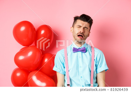 Valentines concept. Sad and heartbroken man crying over break-up, being cheated on lovers day, sobbing and feeling lonely, standing on pink background 81926439