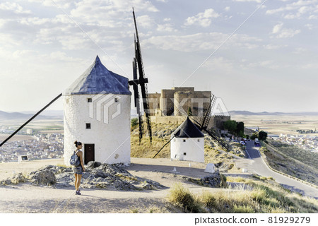 Tourist on a hill with a group of restored windmills and a castle Tourist on a hill with a group of restored windmills and a castle 81929279