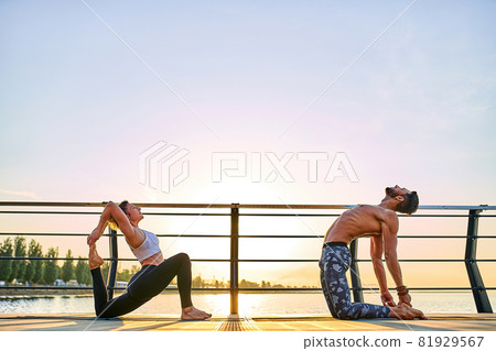 Couple practicing acrobatic yoga together on nature outdoors at sea. 81929567