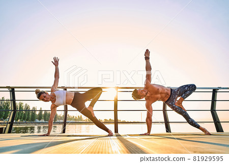 Couple practicing acrobatic yoga together on nature outdoors at sea. 81929595
