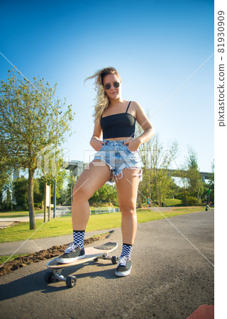 Beautiful young woman with skateboard 81930909