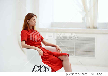 red-haired woman in red dress posing on a chair fashion 81932239