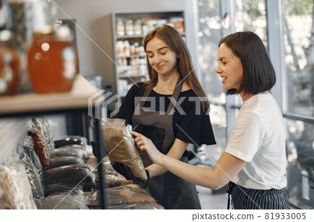 Female seller helps the buyer to choose the product. 81933005