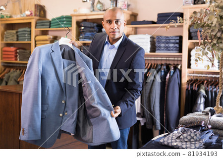 Friendly salesman offering suit in menswear boutique 81934193