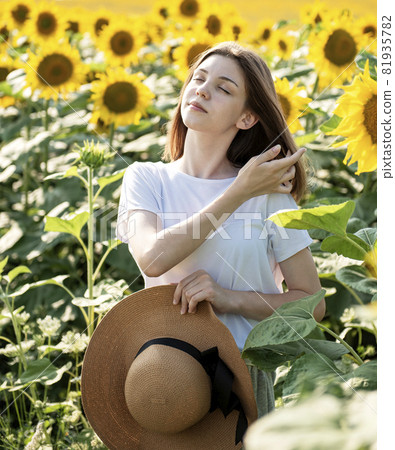 Young beautiful girl walking in the field with sunflowers Young beautiful girl walking in the field with sunflowers 81935782