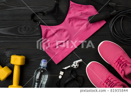 Athlete's set with female clothing, sneakers and bottle of water on dark background Athlete's set with female clothing, sneakers and bottle of water on dark background 81935844