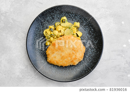 Overhead view of pork schnitzel with potato and pickled cucumber 81936016