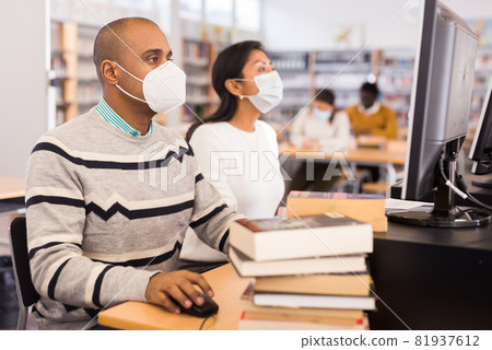 Man in mask studying in computer class Man in mask studying in computer class 81937612