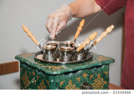 Woman makes turkish coffee on a coffee machine with sand in cezve. Oriental, east coffee. 81939466