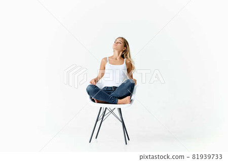 woman sitting on white chair with bent legs emotions lifestyle light background 81939733