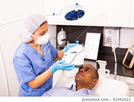 Male client getting face phototherapy procedure in clinic 81942022