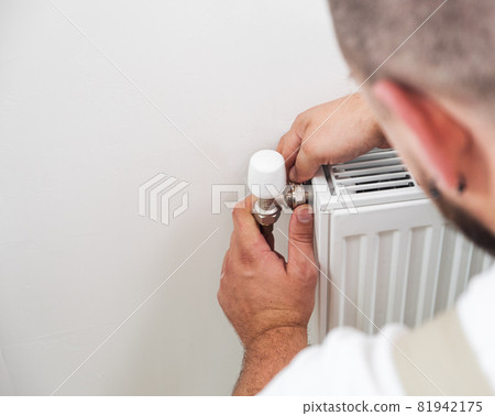 Plumber installing new steel hot water central heating radiator 81942175