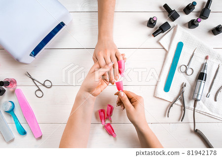 Nail care. Closeup of female hands filing nails with professional nail file in beauty nail salon. Top view 81942178