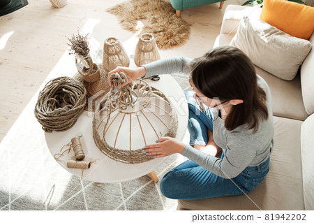 Woman makes handmade diy lamp from jute rope, top view Woman makes handmade diy lamp from jute rope, top view 81942202