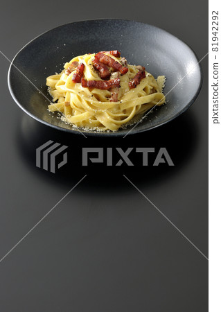 Crispy baked fettuccine carbonara with bacon shot on a black background 81942292