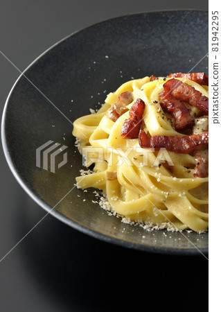 Crispy baked fettuccine carbonara with bacon shot on a black background 81942295