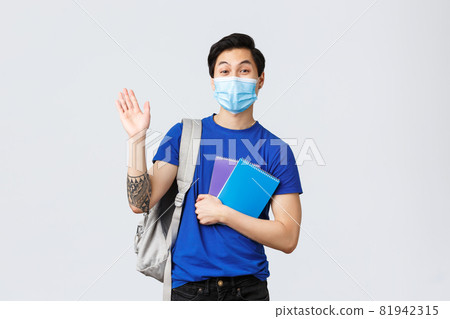 Back to school, studying during covid-19, education and university life concept. Young handsome asian male student, freshman in college waving hand in hello or greeting, holding notebooks Back to school, studying during covid-19, education and university life concept. Young handsome asian male student, freshman in college waving hand in hello or greeting, holding notebooks 81942315