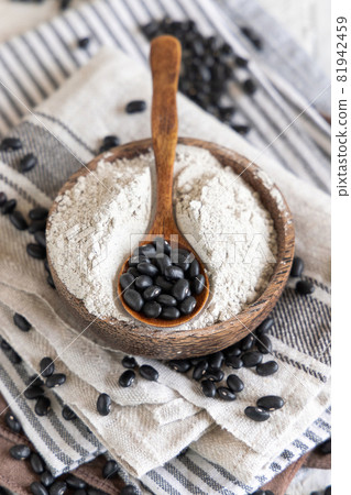 Wooden bowl with black beans flour with a wooden spoon Wooden bowl with black beans flour with a wooden spoon 81942459