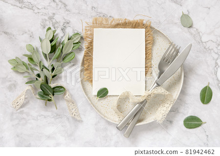 Blank paper card on a plate with eucalyptus branches and ribbons 81942462