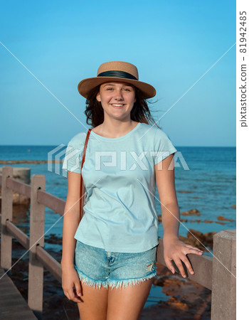Teen girl standing on wooden bridge by the sea 81942485