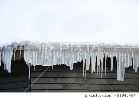 Icicles hang from the roof of a house or building. The onset of cold weather. It is dangerous to walk under icicles. 81943494