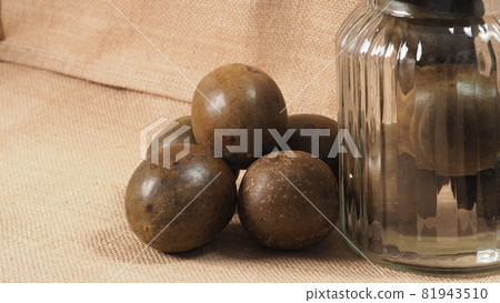 Monk fruit or Luo Han Guo. Dried fruits for healthy sweetener drink. Natural herbal remedy and glass bottle background. Monk fruit drink for who concern health and sugar substitute. Monk fruit or Luo Han Guo. Dried fruits for healthy sweetener drink. Natural herbal remedy and glass bottle background. Monk fruit drink for who concern health and sugar substitute. 81943510