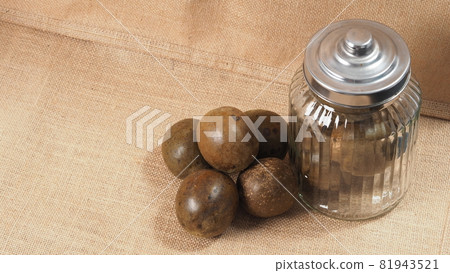 Monk fruit or Luo Han Guo. Dried fruits for healthy sweetener drink. Natural herbal remedy and glass bottle background. Monk fruit drink for who concern health and sugar substitute. Monk fruit or Luo Han Guo. Dried fruits for healthy sweetener drink. Natural herbal remedy and glass bottle background. Monk fruit drink for who concern health and sugar substitute. 81943521