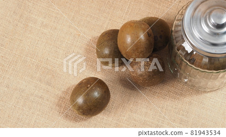 Monk fruit or Luo Han Guo. Dried fruits for healthy sweetener drink. Natural herbal remedy and glass bottle background. Monk fruit drink for who concern health and sugar substitute. Monk fruit or Luo Han Guo. Dried fruits for healthy sweetener drink. Natural herbal remedy and glass bottle background. Monk fruit drink for who concern health and sugar substitute. 81943534