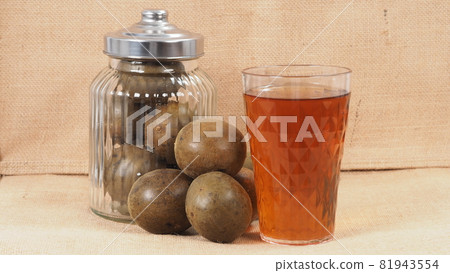 Monk fruit or Luo Han Guo. Dried fruits for healthy sweetener drink. Natural herbal remedy and glass bottle background. Monk fruit drink for who concern health and sugar substitute. Monk fruit or Luo Han Guo. Dried fruits for healthy sweetener drink. Natural herbal remedy and glass bottle background. Monk fruit drink for who concern health and sugar substitute. 81943554