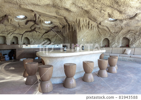 Patio in artificial rocky cave with marble table, wooden chairs, sofa and kitchen cabinets Patio in artificial rocky cave with marble table, wooden chairs, sofa and kitchen cabinets 81943588