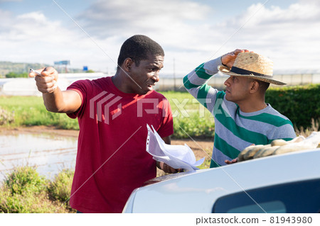 Two farmers with papers arguing on farm 81943980