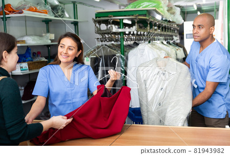 Laundry workers giving clothes to client 81943982