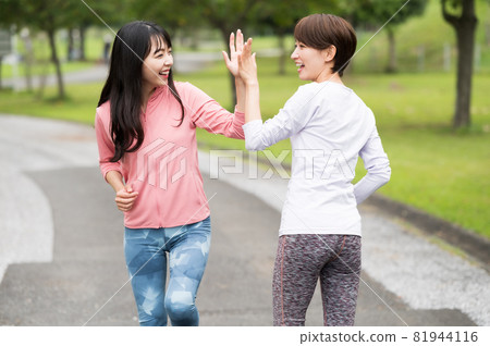 Two women giving a high five while jogging Two women giving a high five while jogging 81944116