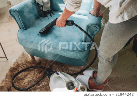 Hand cleaning a armchair with steam cleaner, Home cleaning conce Hand cleaning a armchair with steam cleaner, Home cleaning conce 81944248
