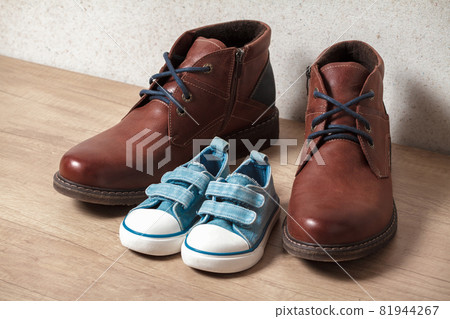 Men's and children's shoes on a wooden floo 81944267