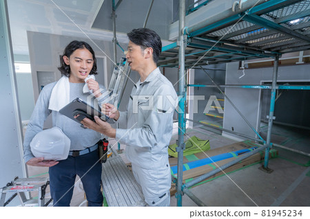 一名工地主管和兩名木匠在建築工地邊看平板電腦邊交談 一名工地主管和兩名木匠在建築工地邊看平板電腦邊交談 81945234