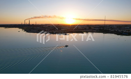 The boat sails in the bay at sunset near the city 81945576