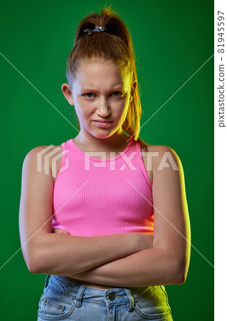 unsatisfied redhead teenager on the green background. unsatisfied redhead teenager on the green background. 81945597