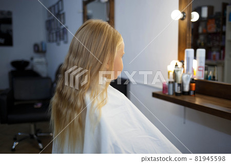 hairdresser straightens hair of a little girl in a beauty salon 81945598