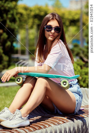 beautiful skateboarder girl with skateboard sitting outdoors beautiful skateboarder girl with skateboard sitting outdoors 81945854
