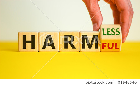 From harmful to harmless. Male hand turns the cube and changes word 'harmful' to 'harmless'. Beautiful yellow table, white background. Business and harmful or harmless concept. Copy space. From harmful to harmless. Male hand turns the cube and changes word 'harmful' to 'harmless'. Beautiful yellow table, white background. Business and harmful or harmless concept. Copy space. 81946540