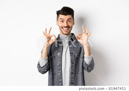 Happy guy say yes, smiling and showing okay signs, like good product, nod in approval and make satisfied face, praise excellent work, standing on white background 81947451