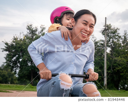 Happy mother enjoy having fun riding kids bicycle with cute daughter in summer park. Family spend their free time together on vacation. Happy mother enjoy having fun riding kids bicycle with cute daughter in summer park. Family spend their free time together on vacation. 81948446