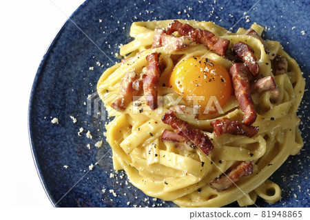 A bird's-eye view of Fettuccine's carbonara with egg yolk and crispy bacon on a white background A bird's-eye view of Fettuccine's carbonara with egg yolk and crispy bacon on a white background 81948865