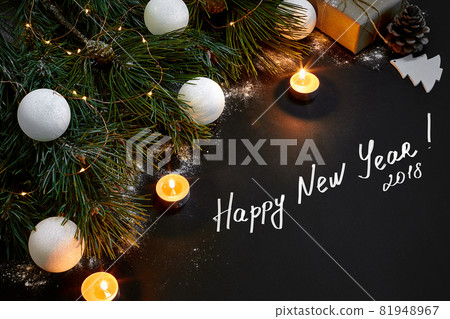 Christmas. Xmas toys, burning candles and spruce branch on black background top view. Space for text Christmas. Xmas toys, burning candles and spruce branch on black background top view. Space for text 81948967