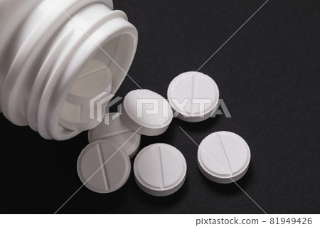 White tablets are poured from a jar onto a table, close-up. Medicine concept 81949426