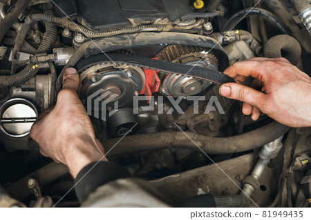 Auto mechanic changes the timing belt in the car, close-up Auto mechanic changes the timing belt in the car, close-up 81949435