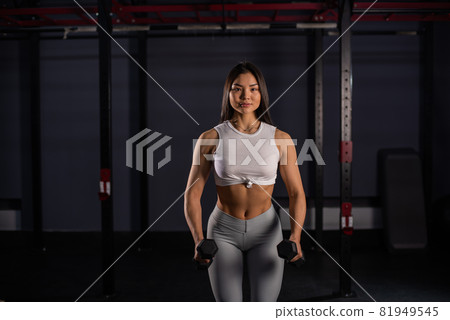Asian woman doing exercises with dumbbells in the gym. 81949545