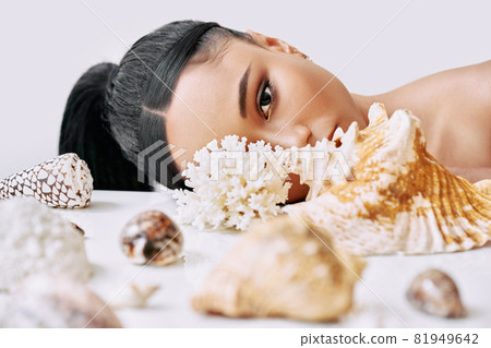 Fashion portrait of beautiful african american woman with different seashells looking through conch 81949642